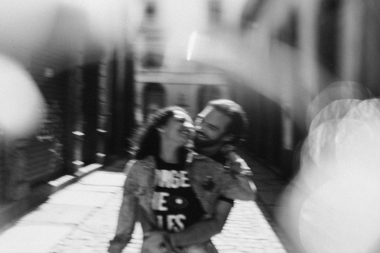 Happy couple embraces on a sunlit street in Rio de Janeiro, Brazil, in a moody monochrome style.