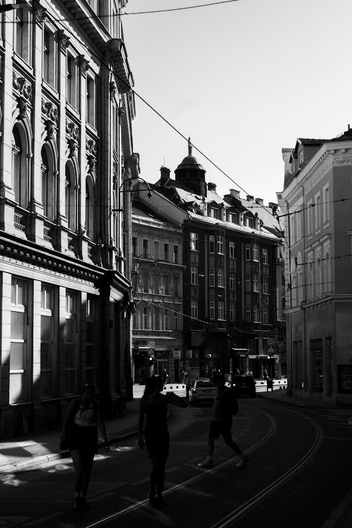 A moody black and white photo capturing an urban street scene with pedestrians.